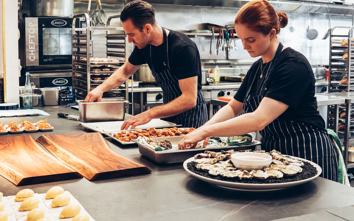 Two Restaurant Employees Prepare Food In The Back Of The House