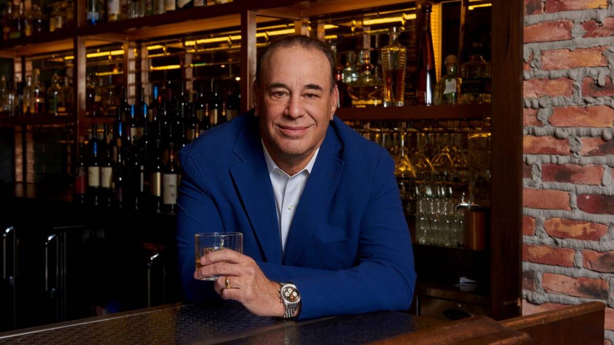 Jon Taffer holding a drink in a bar setting.