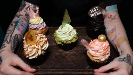 BITE ME Cupcakery holding board of different cupcakes.