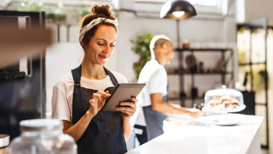 Waitress using digital tablet to view and manage orders in a coffee shop.