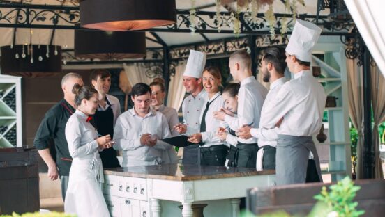 Restaurant manager and his staff in terrace. interacting to head chef in restaurant.