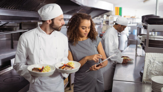 Restaurant manager in kitchen with chef stock image.