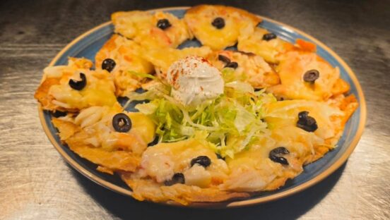 Chi-Chi's Seafood Nachos_ Crisp tortilla chips are loaded with crab, shrimp, creamy seafood sauce, cheddar cheese, sour cream and black olives for a shareable appetizer packed with coastal flavor.