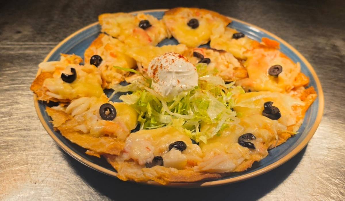Chi-Chi's Seafood Nachos_ Crisp tortilla chips are loaded with crab, shrimp, creamy seafood sauce, cheddar cheese, sour cream and black olives for a shareable appetizer packed with coastal flavor.